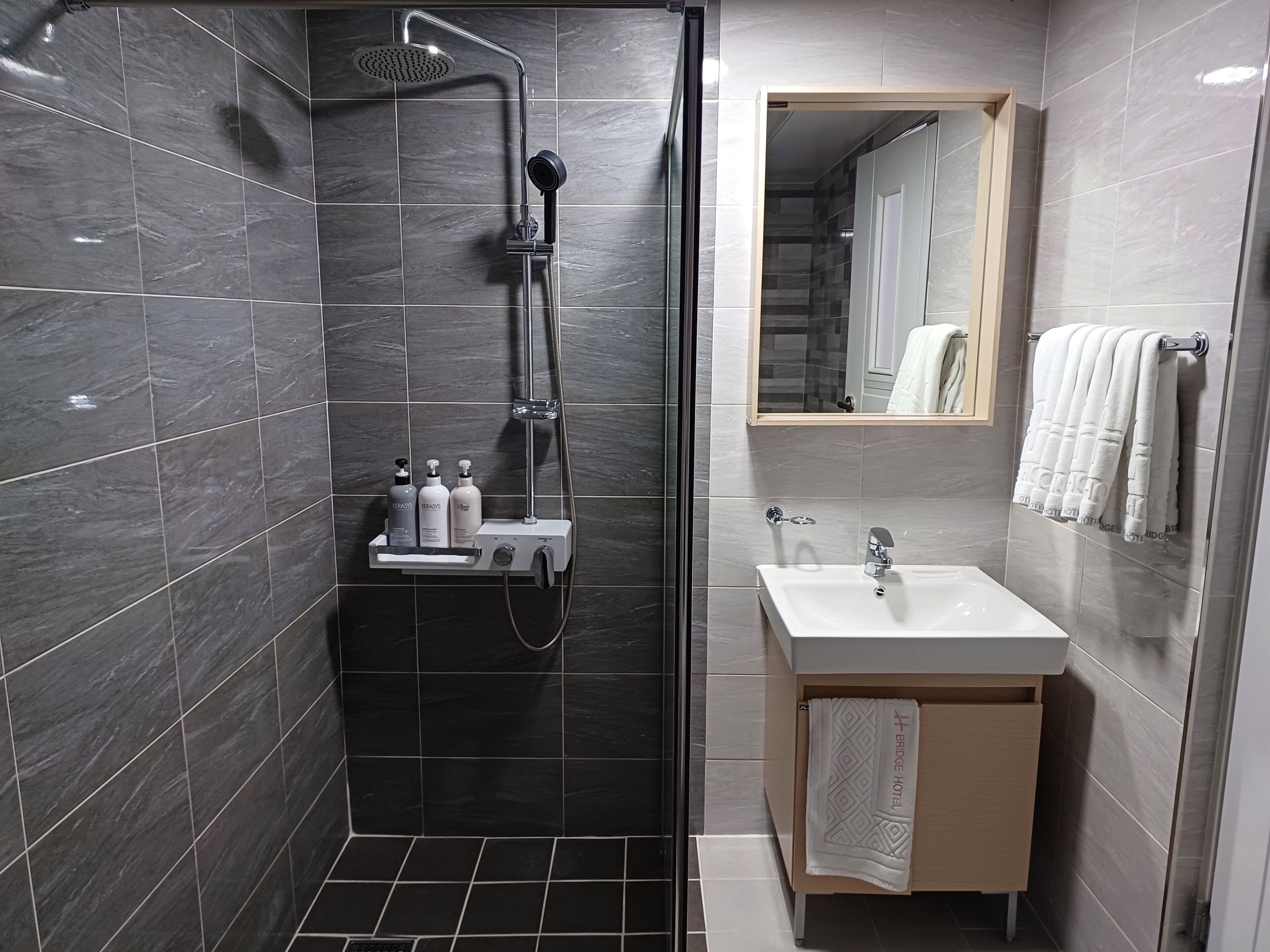 A modern bathroom with a shower, a sink, and a mirror.