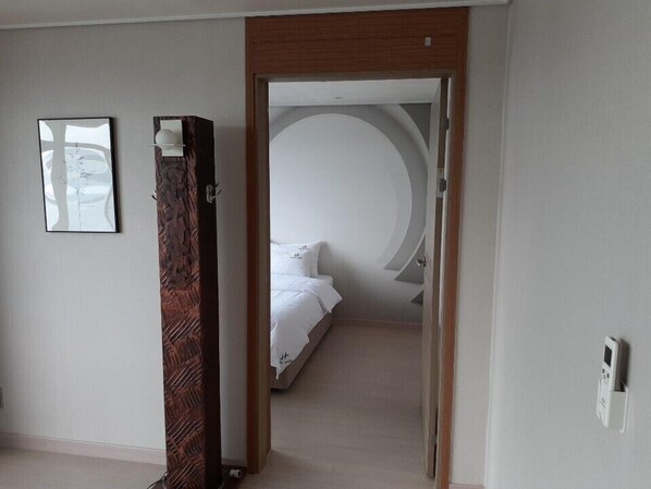 Una habitación de hotel con una cama, una puerta de madera y una lámpara fijada a la pared.