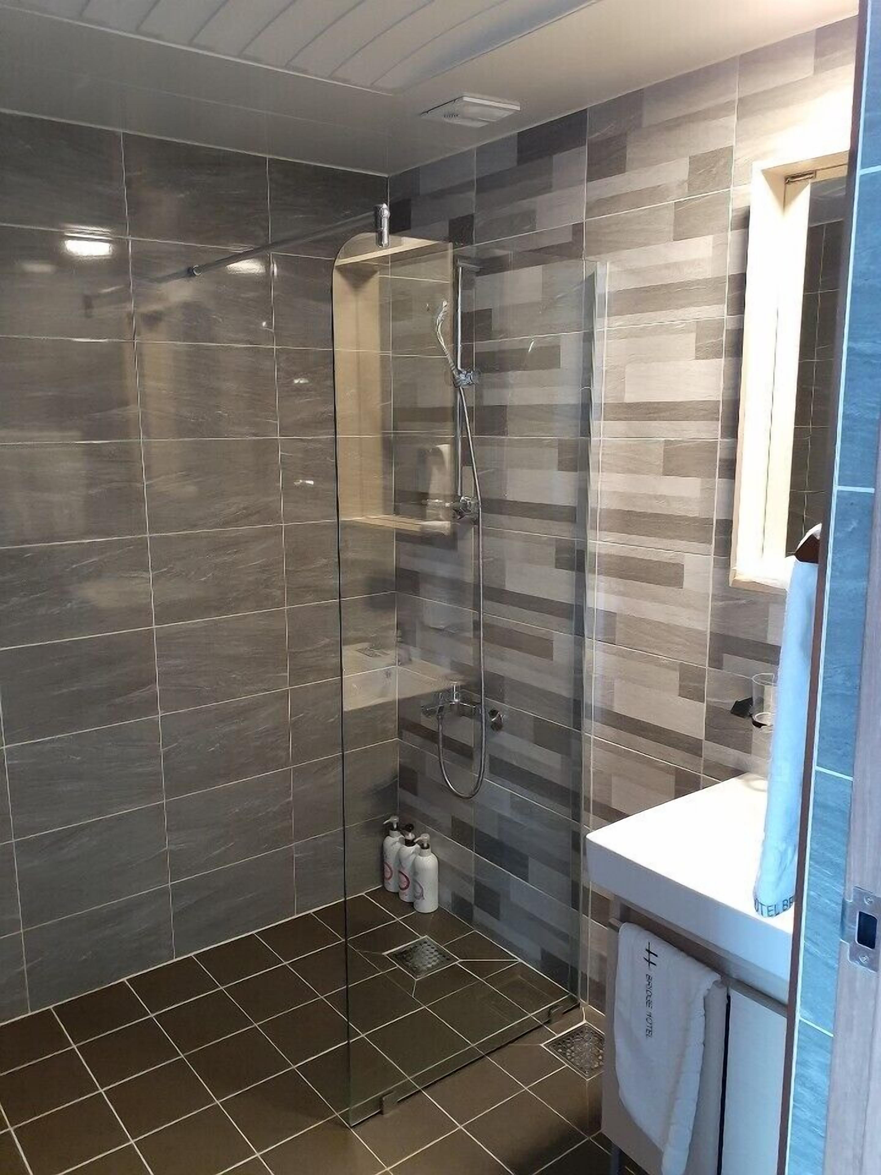 A modern bathroom with a glass-enclosed shower, a white sink, and a mirror.