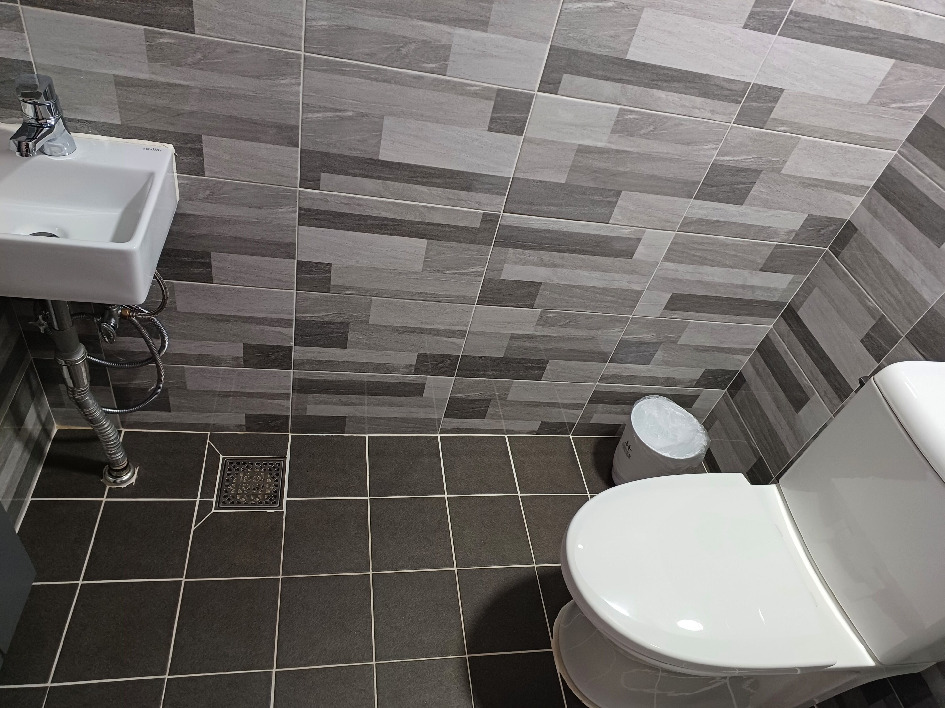 A bathroom with a modern design, featuring a sink, toilet, and a shower area.