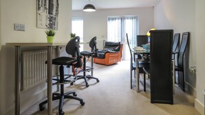 A modern office space with a desk, office chairs, a sofa, and a dining table.