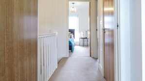 A hallway with a wooden floor, white walls, and a ceiling light fixture.