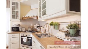 Un appartement de trois chambres doté d’une cuisine avec des meubles blancs, un four à micro-ondes, une cuisinière et un évier.
