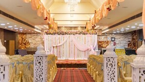 A ceremonial hall with a stage, floral decorations, and a carpeted aisle. - Hotel Maple Delite (Lucknow)