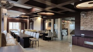 A modern hotel lobby with a long reception desk, multiple seating areas, and a decorative wall. - Hotel Maple Delite (Lucknow)