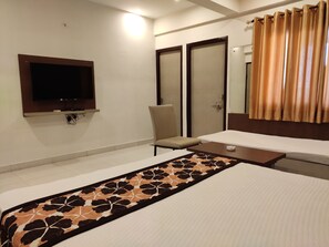 A hotel room with a bed, a chair, a television, and a wardrobe. - Hotel Maple Delite (Lucknow)