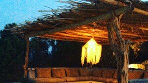 Ein Sitzbereich im Freien mit einer Holzw pergola, einer hängenden Laterne und einer Steinsitzbank.