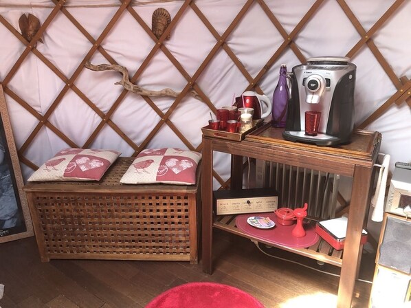 Une pièce chaleureuse avec un banc en bois, une petite table sur laquelle se trouve une machine à café et un radiateur.