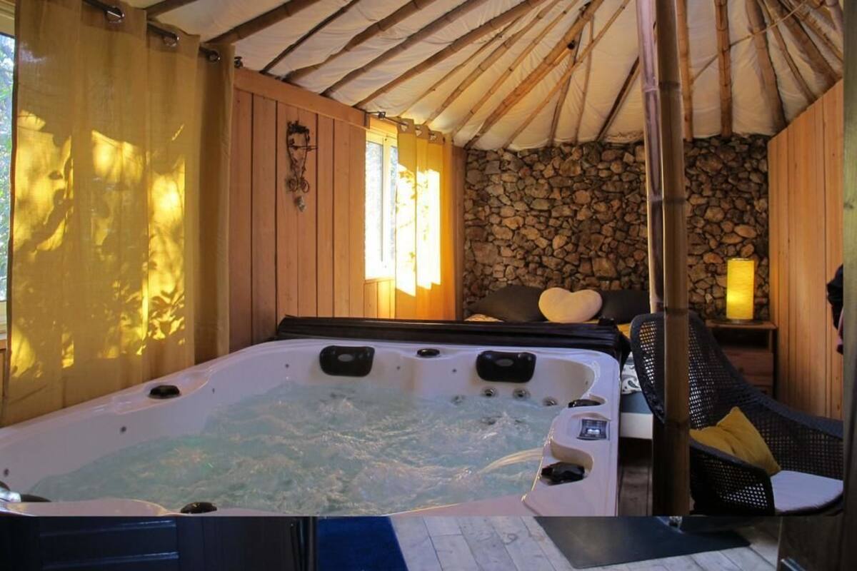 Un bain à remous dans un chalet en bois, avec un mur en pierre et un hamac.