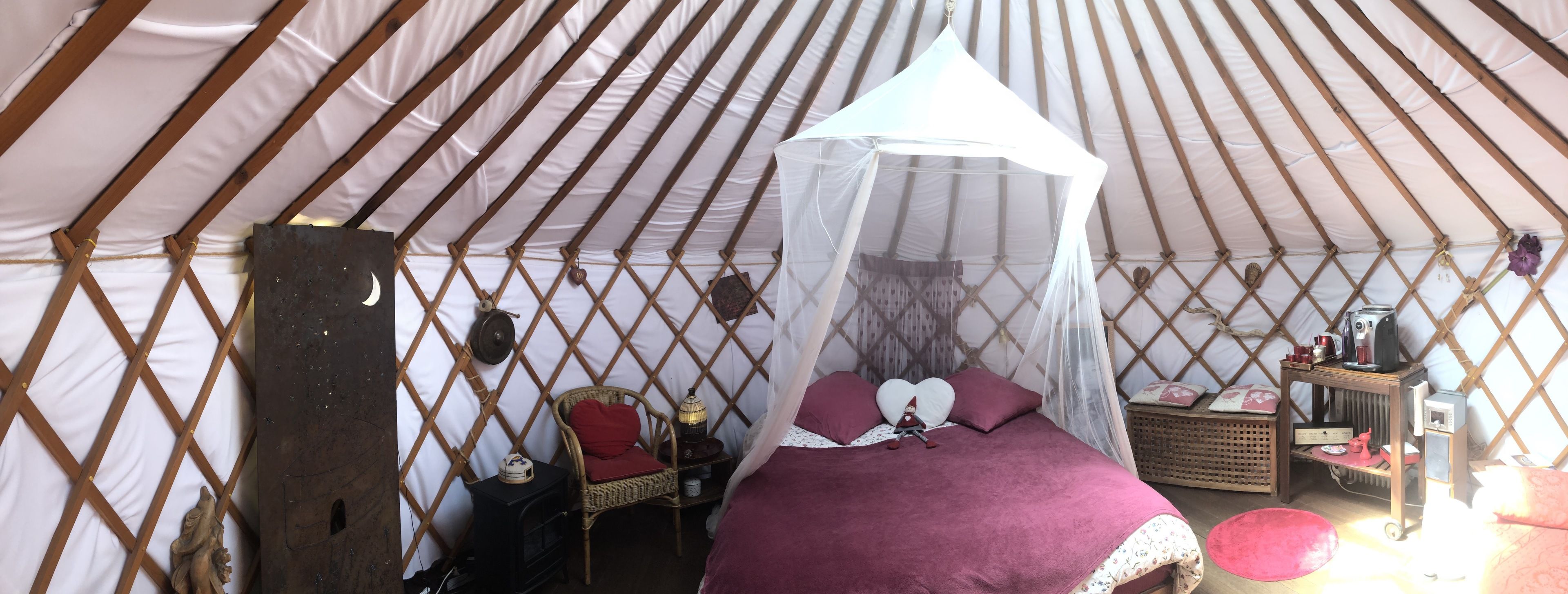 Acogedor interior de una yurta con cama, una mesita y una silla.