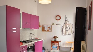 A compact kitchen with pink cabinets, a gas stove, and a small dining table.
