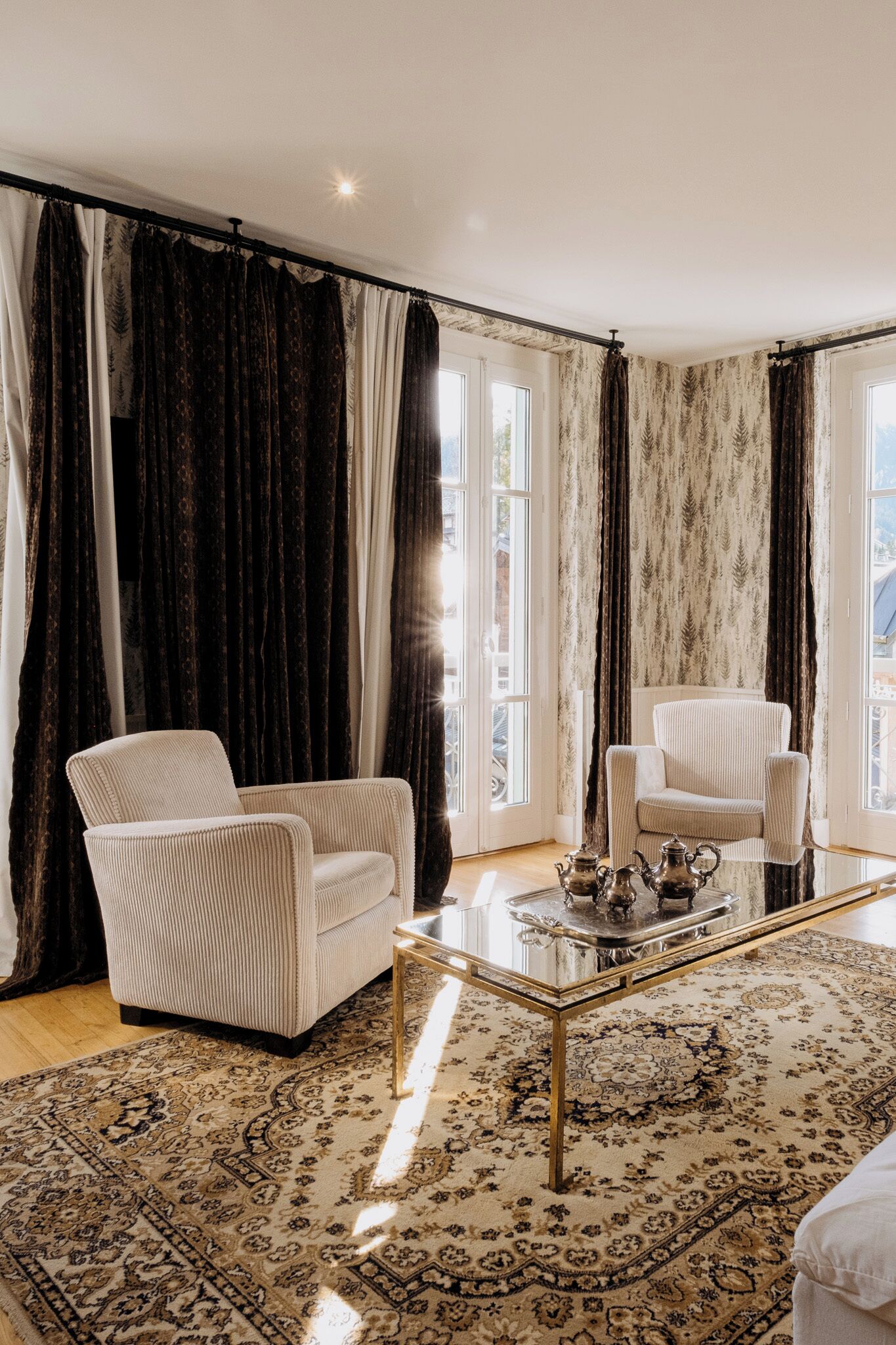 Une pièce comprenant deux fauteuils, une table basse en verre et un tapis à motifs.