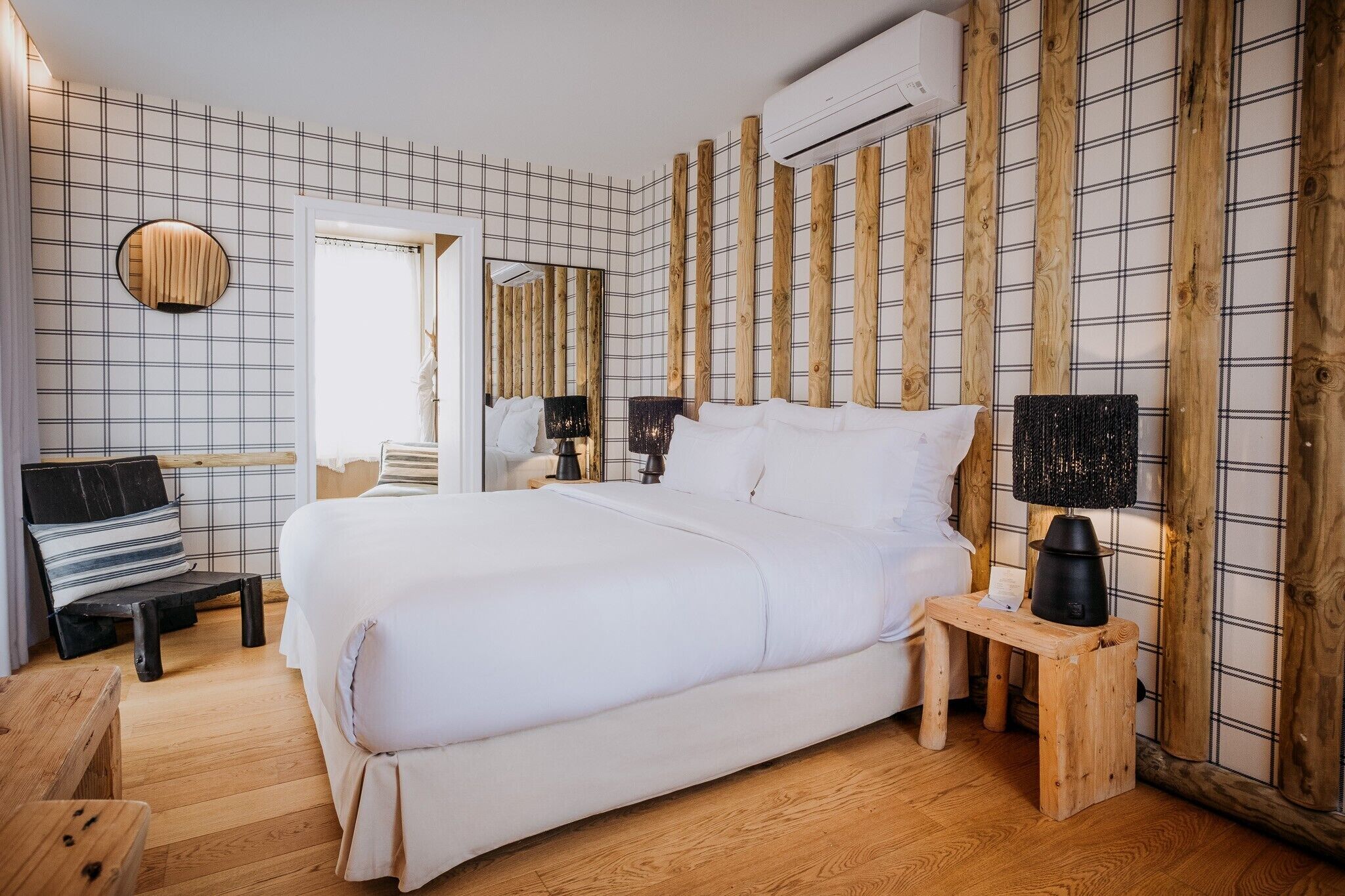 A bedroom with a large bed, a bedside table, a chair, and a mirror.