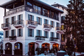 Een hotel met meerdere verdiepingen, balkons, gebogen ramen en een bord met restaurant.