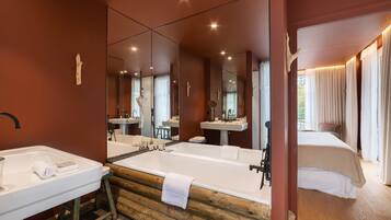 A modern bathroom with a wooden vanity, a large bathtub, and a separate shower area.