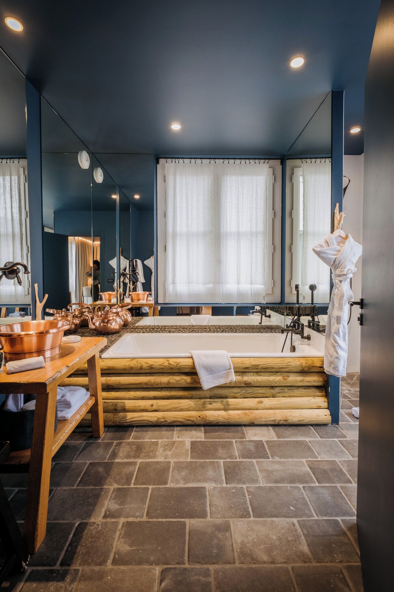 Une salle de bain moderne avec une baignoire, un plancher en bois et un grand miroir.
