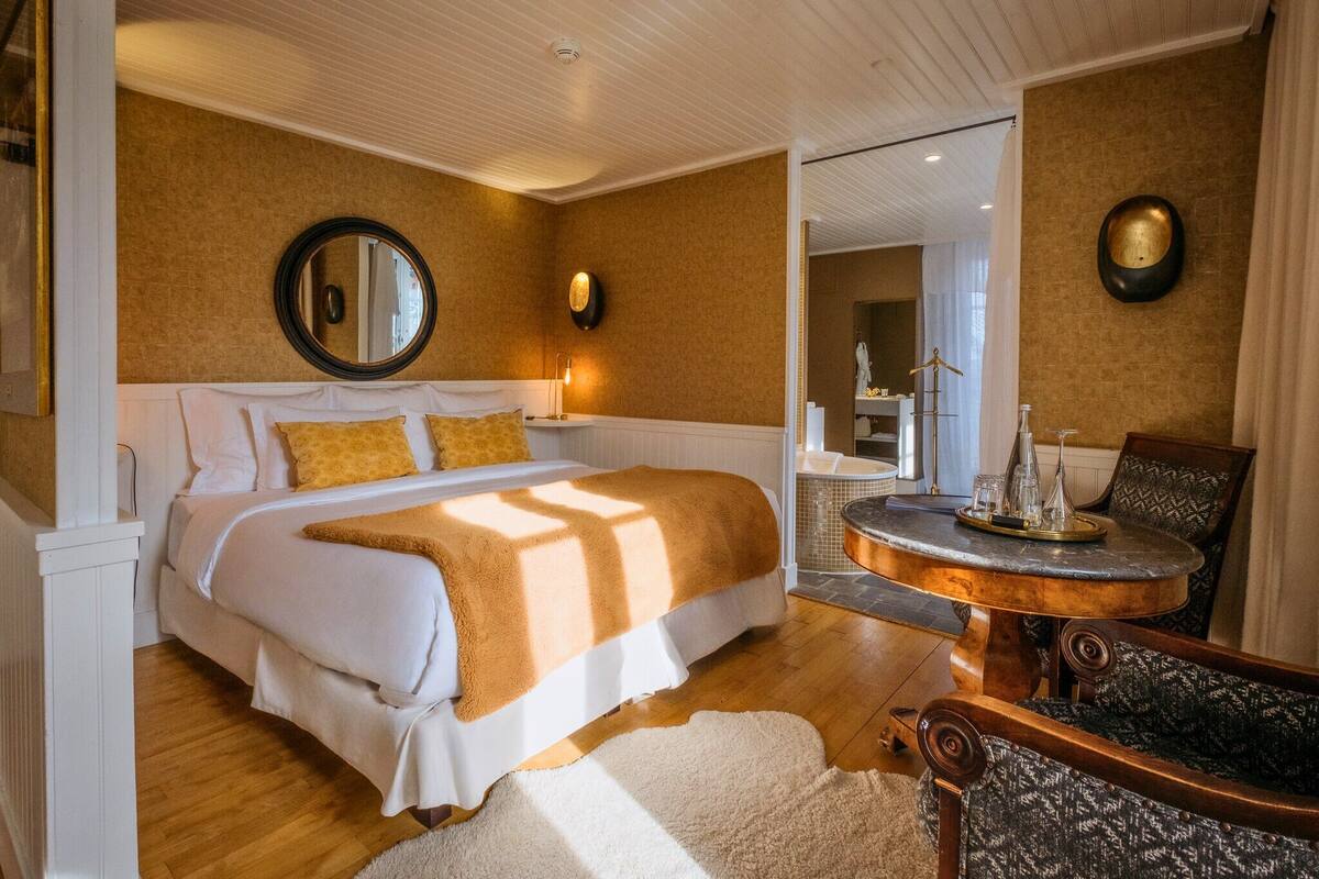 A bedroom with a large bed, a round table with a tray, and a chair.