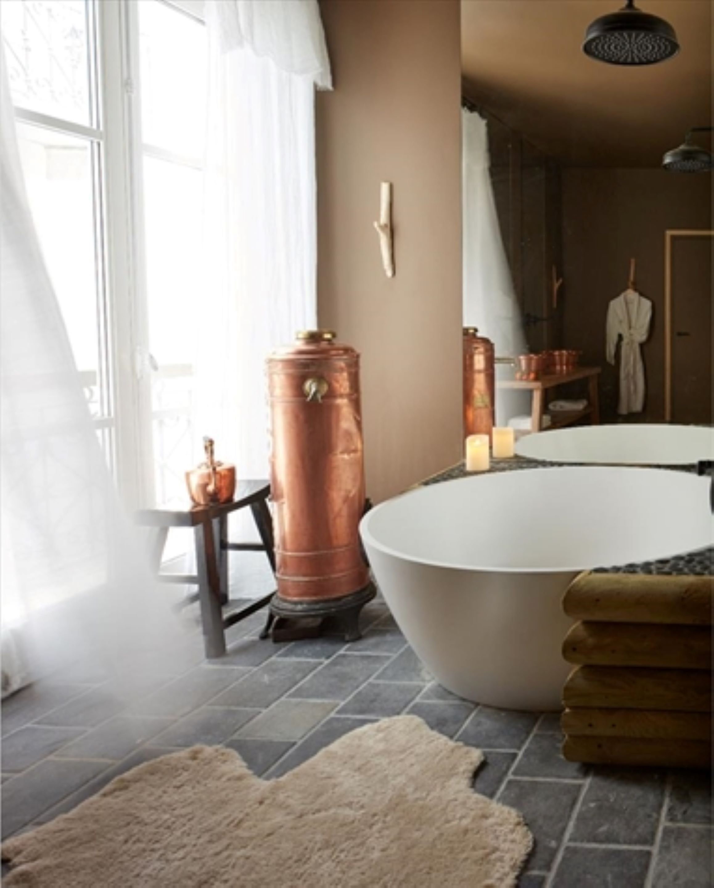 Ein Badezimmer mit einer großen Badewanne, einem Kupfer-Warmwasserbereiter und einem rustikalen Teppich.