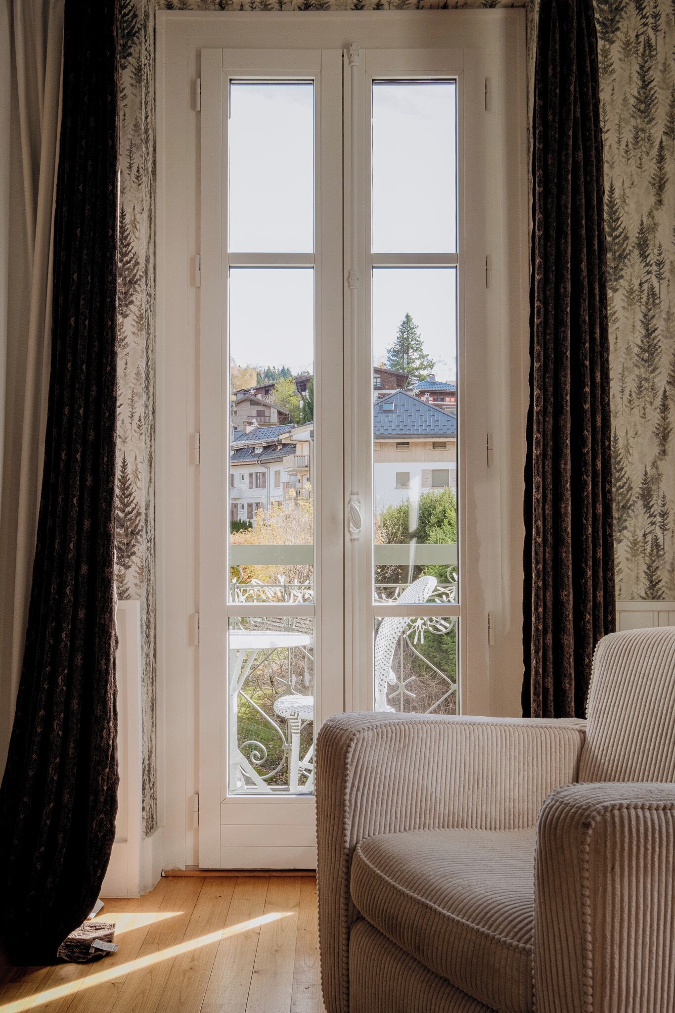 Una habitación con un ventanal grande, una silla y vistas a edificios.