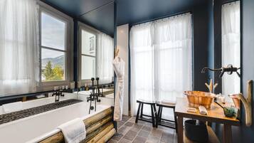 Une salle de bain avec une baignoire, un banc en bois et une table avec un lavabo et une serviette.