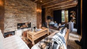 A cozy living room with a stone wall, a fireplace, a wooden coffee table, and a sofa.