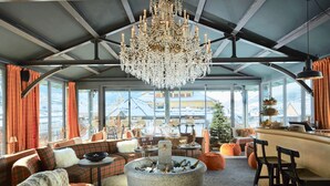 A cozy lounge area with a stone fireplace, plush seating, and a large chandelier.