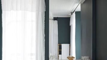 A bathroom with a white vanity, a mirror, and a bench with towels.