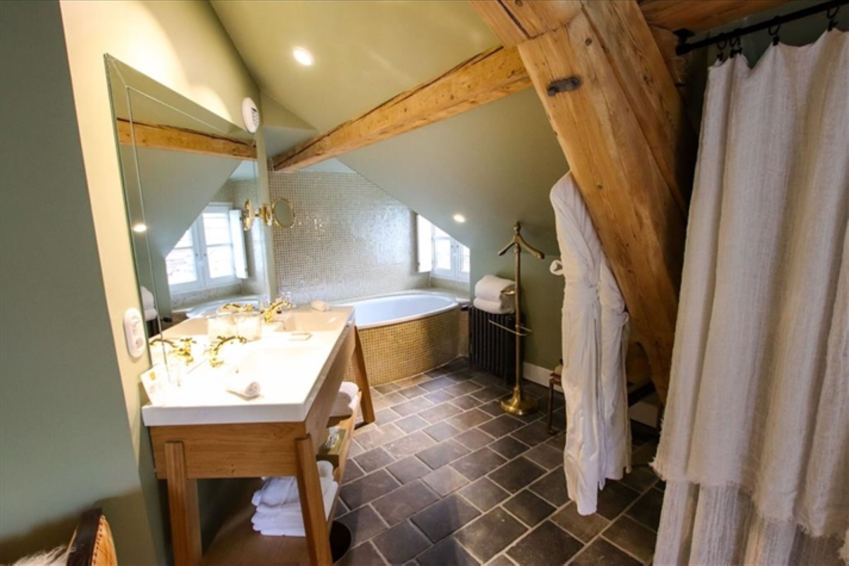 A bathroom with a wooden ceiling, a bathtub, a vanity with a mirror, and a towel rack.