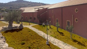 Un edificio de fachada roja, un sendero de piedra y un pequeño árbol.