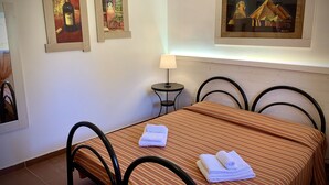 Una habitación de hotel con una cama, una mesita de noche con una lámpara y dos cuadros en la pared.