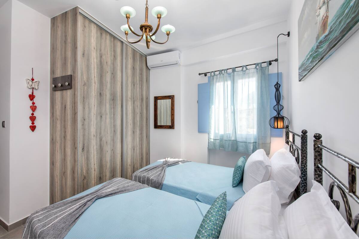 Un dormitorio con dos camas, una pared decorativa de madera, una araña y un cuadro.