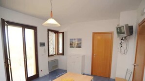 Una cucina piccola e luminosa con un tavolo di legno, una sedia e un televisore montato a parete.