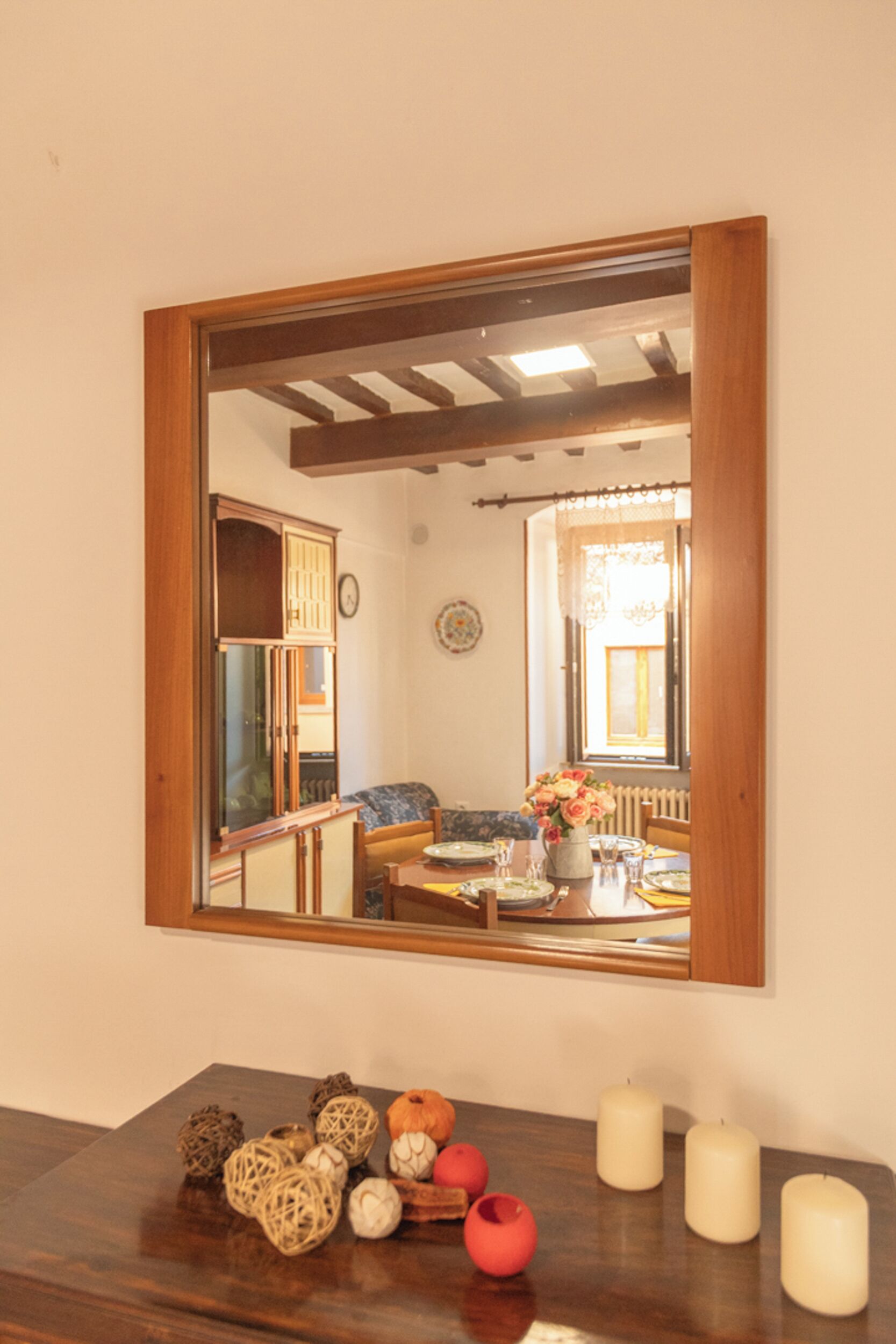 Un coin repas avec une table en bois, des bougies et un miroir qui reflète la pièce.