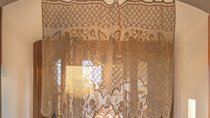 Un umbral con un encaje decorativo, una puerta de madera y vista de un interior rústico con una pared de azulejos y una maceta de cerámica.