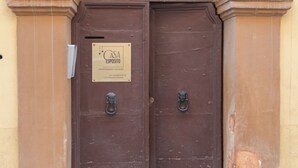 Una doble puerta de madera con un cartel encima, una reja metálica sobre la puerta y un escalón que lleva a ella.
