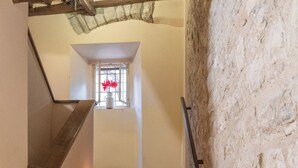 Una escalera con velas, una ventana con flores rojas y objetos decorativos en los peldaños.