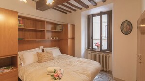 Un dormitorio con una cama grande, estanterías de madera, un radiador y una ventana con vistas.