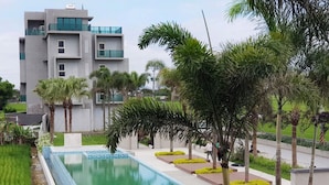 Un bâtiment moderne doté d’une piscine, entouré de palmiers et de verdure.