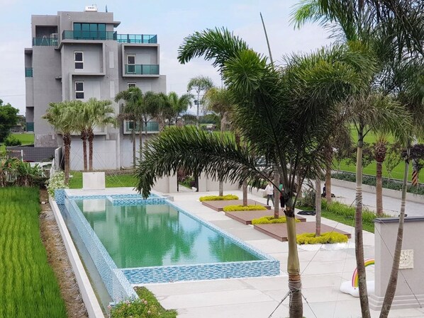 A modern building with a swimming pool, surrounded by palm trees and greenery. - Chance Villa 262 (Jiaoxi)