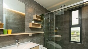 Une salle de bain moderne avec une douche à parois de verre, un grand miroir et des étagères intégrées pour ranger les articles de toilette.