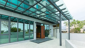Un bâtiment moderne doté de grandes fenêtres en verre, d’un auvent d’entrée en métal et d’une façade en béton.