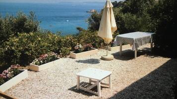 Un espace extérieur aménagé avec une table et des chaises, une table couverte et un parasol.