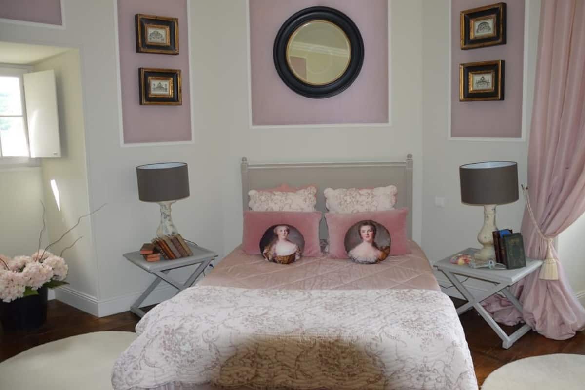 A bedroom with a bed, two bedside tables, a mirror, and framed pictures on the wall.