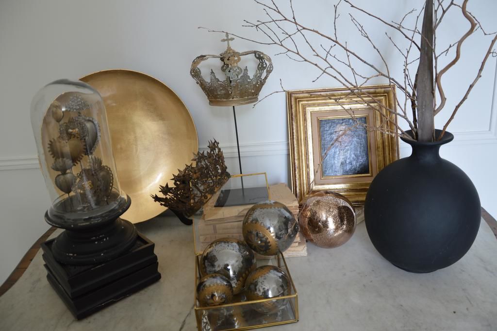 A collection of decorative items including a glass dome, a golden plate, a black vase, and a framed picture.