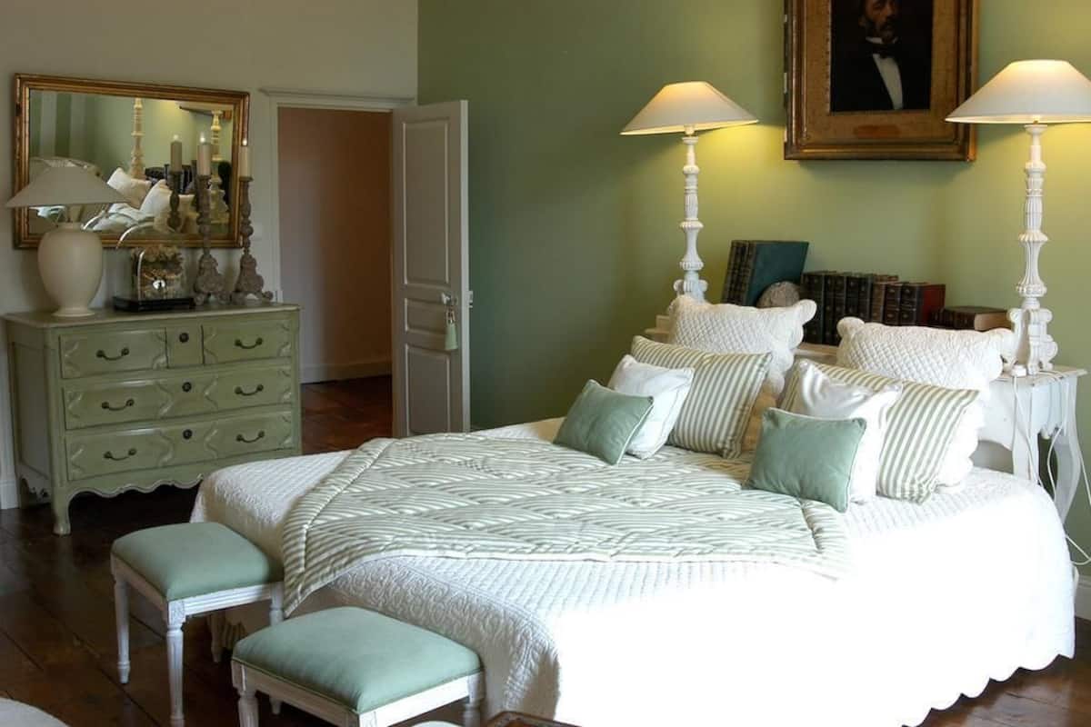 A bedroom with a bed, two nightstands, a dresser, a mirror, and a framed picture on the wall.