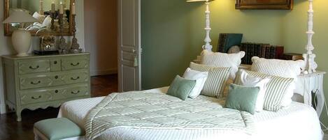 A bedroom with a bed, two nightstands, a dresser, a mirror, and a framed picture on the wall.