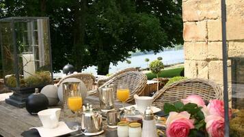 Colazione all'aperto con mobili in vimini, un tavolo in vetro e vista sul mare.