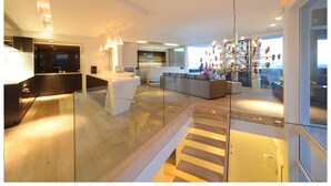 A modern living room with a glass railing, a staircase, and a chandelier. - Ebb Tide (Cape Town)