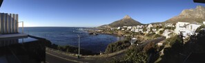 A coastal town with a prominent mountain, a road leading to the beach, and residential buildings.
