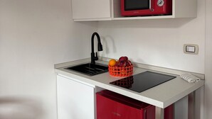 A compact kitchen with a sink, a red refrigerator, a microwave, and a fruit basket on the countertop. -  Artdeco Luxury suite Pescarenico 2 (Lecco)
